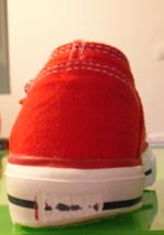 Roter Chucks-mäßiger Kinderturnschuh mit stark auf einer Seite abgelaufener Sohle